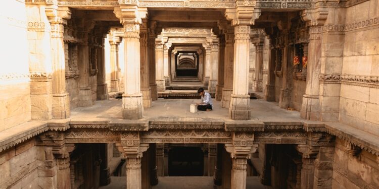 A woman descends the intricate stone steps of one of India's ancient stepwells in Rajasthan in golden morning light