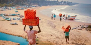 A woman selecting fresh fish at a bustling Indian coastal market, representing the heart of coastal cuisine traditions