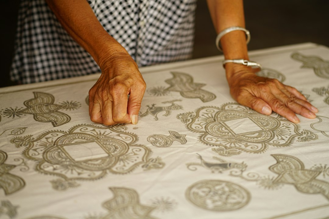 A person holding up a freshly completed block printing piece on fabric, showing the creation of Indian wooden stamps