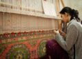 A skilled artisan woman works on a handloom in a regional craft export workshop in India