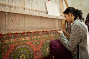A skilled artisan woman works on a handloom in a regional craft export workshop in India