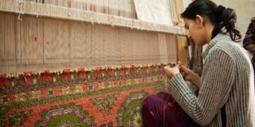 A skilled artisan woman works on a handloom in a regional craft export workshop in India