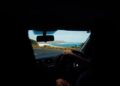 A traveller on the wheel enjoying coastal drives in India with green hills and the Arabian Sea visible through the windscreen