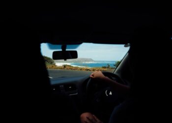 A traveller on the wheel enjoying coastal drives in India with green hills and the Arabian Sea visible through the windscreen