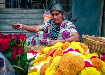 woman-arranging-pookalam-flowers-unsplash - INDIAwebzine A woman carefully places flowers to create a pookalam design during the Onam festival celebration at her home entrance