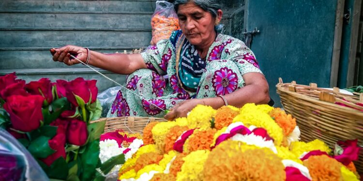 woman-arranging-pookalam-flowers-unsplash - INDIAwebzine A woman carefully places flowers to create a pookalam design during the Onam festival celebration at her home entrance