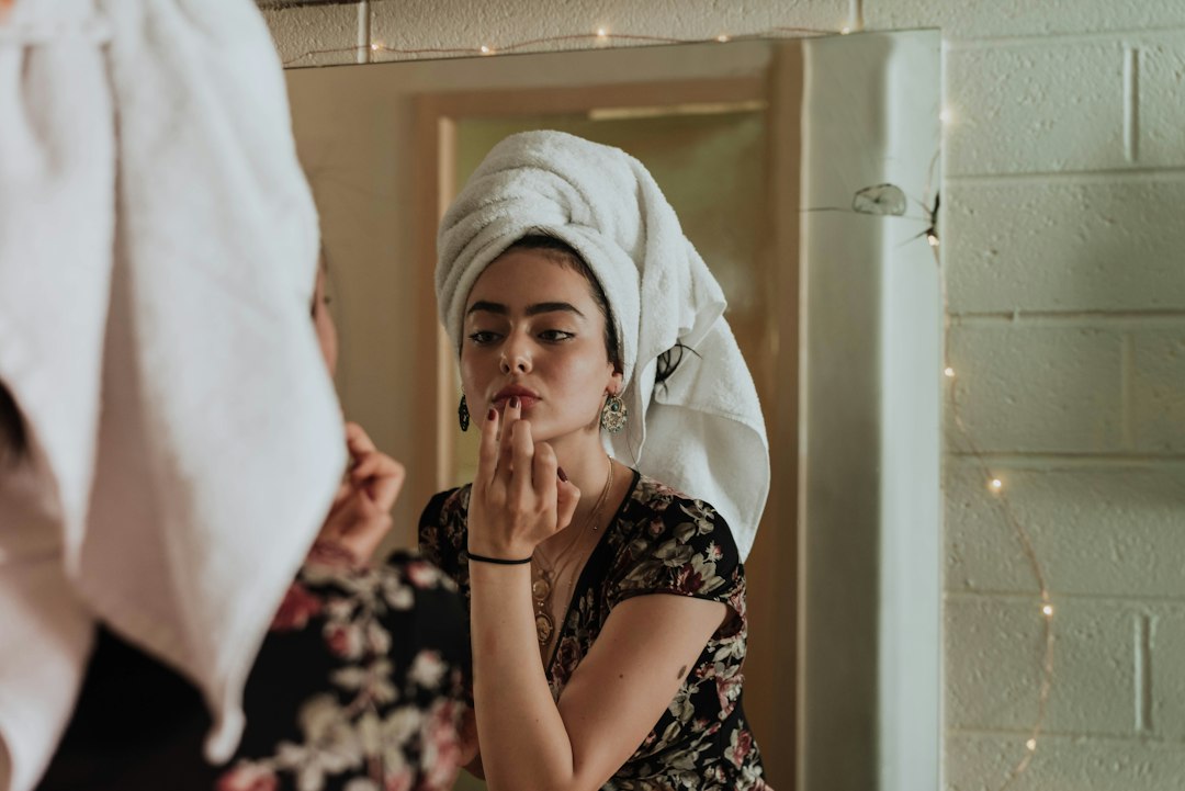 A woman examining her radiant complexion in a mirror after consistent use of kumkumadi oil