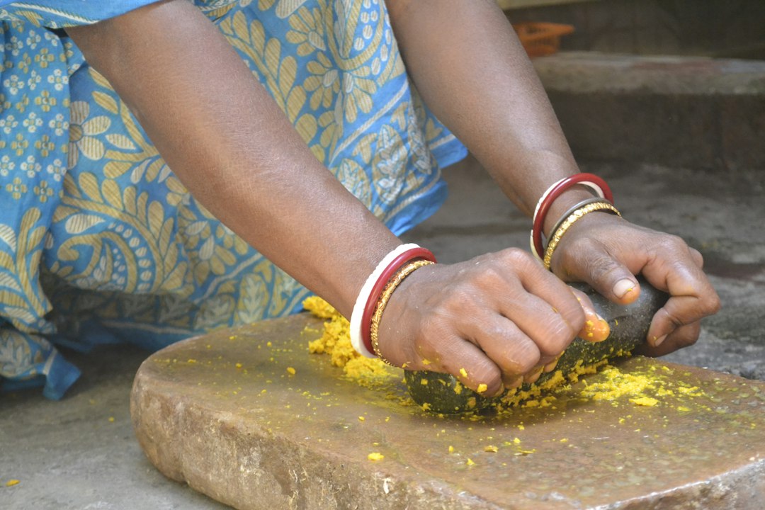 A woman mixing turmeric and gram flour to prepare homemade ubtan in her kitchen