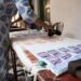 woman-pressing-wooden-stamp-fabric-unsplash - INDIAwebzine A woman carefully pressing an Indian carved wooden stamp onto cotton fabric during a block printing session at home