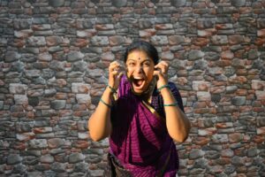 A female vocalist performing Carnatic music on stage at a South Indian concert hall