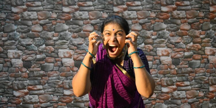 A female vocalist performing Carnatic music on stage at a South Indian concert hall