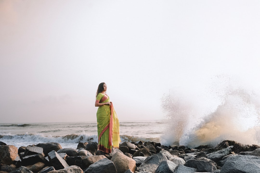 A woman walking alone on a quiet beach in India, the kind of uncrowded shore that rewards post-monsoon coastal drives