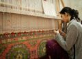 A weaver at her loom building handloom inventory ahead of the festive season in a traditional Indian weaving village.