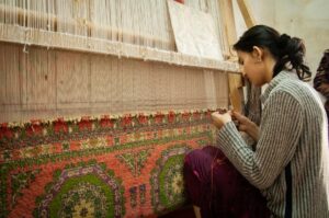 A weaver at her loom building handloom inventory ahead of the festive season in a traditional Indian weaving village.