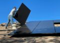 Homeowner inspecting a rooftop solar panel installation on an Indian house