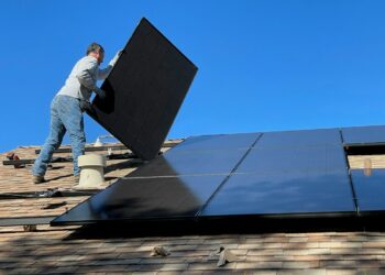 Homeowner inspecting a rooftop solar panel installation on an Indian house