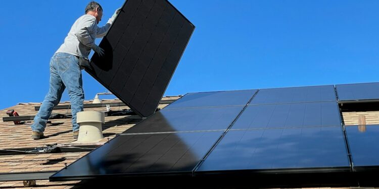 Homeowner inspecting a rooftop solar panel installation on an Indian house