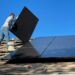 Homeowner inspecting a rooftop solar panel installation on an Indian house