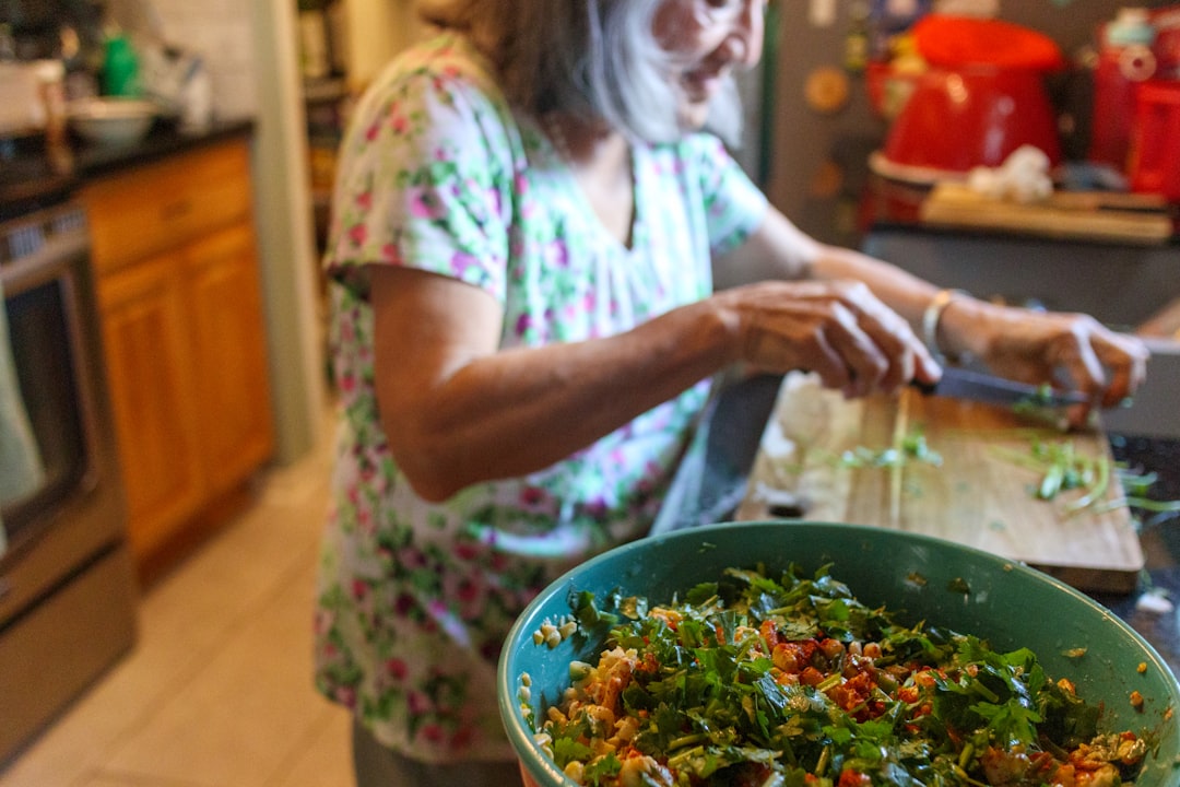 Une jeune femme indienne triant les épluchures de légumes dans un bac de compostage dans sa cuisine d'appartement