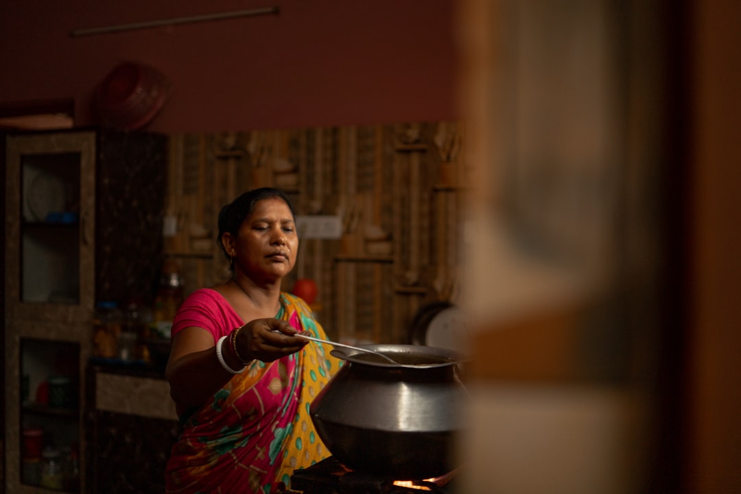 Una abuela enseña a su nieta una receta tradicional, mostrando cómo la diáspora india transmite el patrimonio culinario.