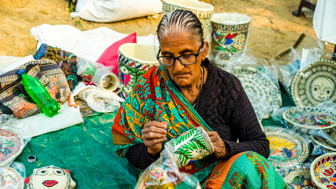 Una mujer artesana india revisando los precios hechos a mano junto a sus productos artesanales