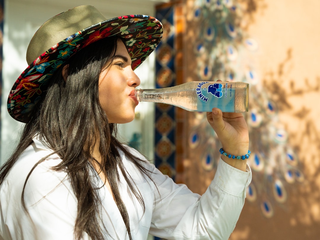 Una mujer india joven bebiendo agua embotellada limpia en un mercado callejero, protegiendo su salud intestinal durante la temporada del monzón