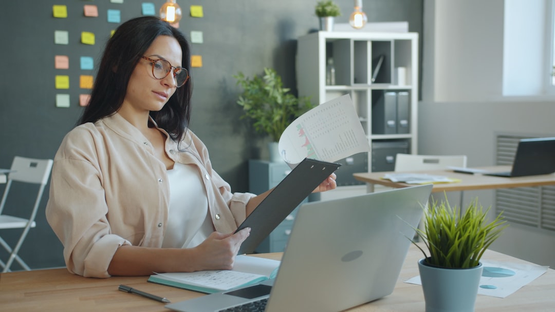 Una mujer profesional india enfocada revisando un informe anual en su escritorio antes de realizar su primera inversión en acciones