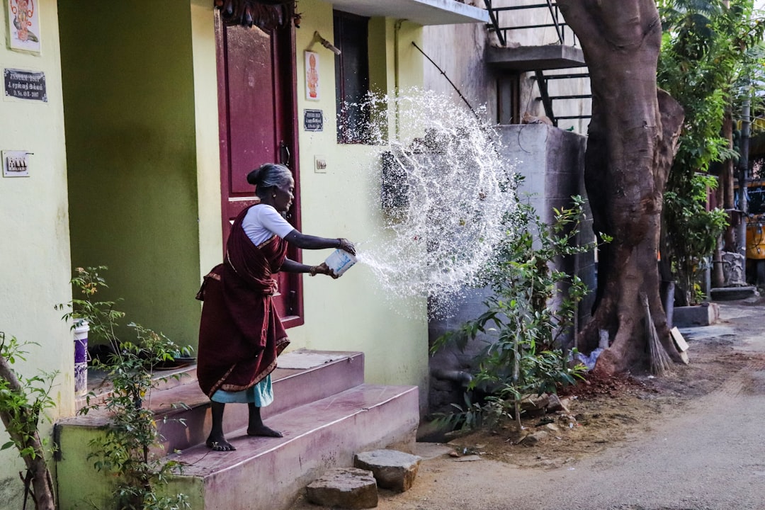 Une femme utilisant son installation de récupération des eaux de pluie sur le toit pendant la saison de mousson dans une maison indienne