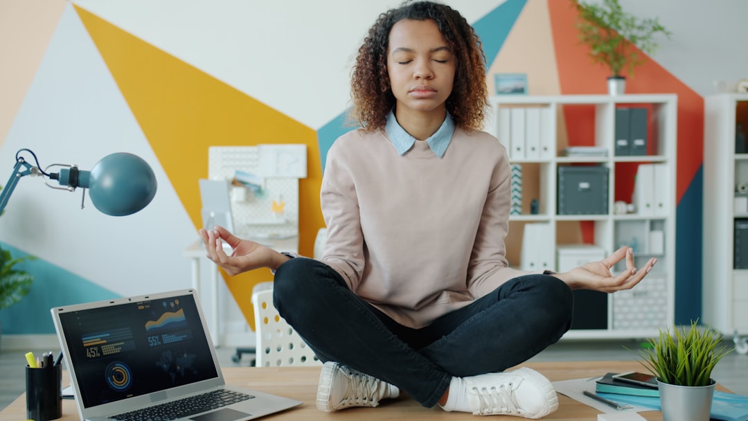 Mujer india practicando ejercicios de respiración pranayama en su escritorio de la oficina en casa con los ojos cerrados