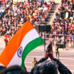 Una mujer con vestimenta tradicional sostiene la bandera tricolor india en una ceremonia de celebración del Día de la Independencia de la diáspora india en el extranjero.