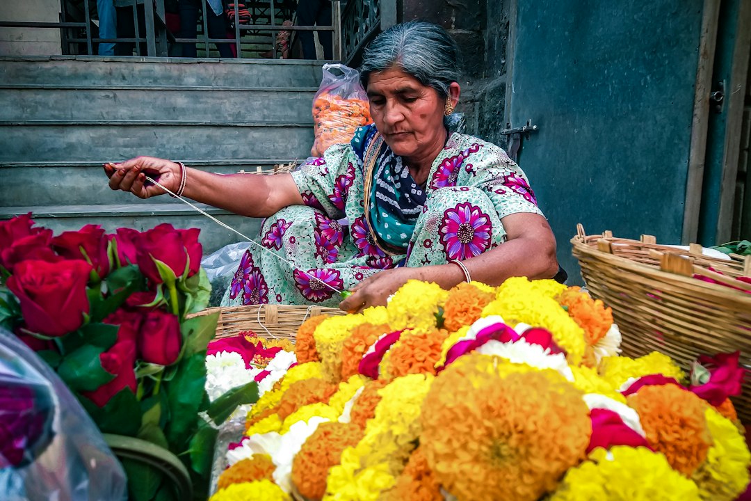 Una mujer coloca cuidadosamente flores para crear un diseño de pookalam durante la celebración del festival Onam en la entrada de su casa